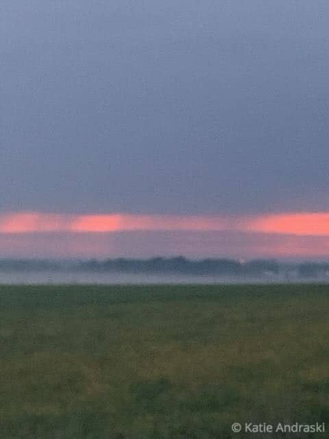 Sunset with pink and orange hues over a foggy landscape.