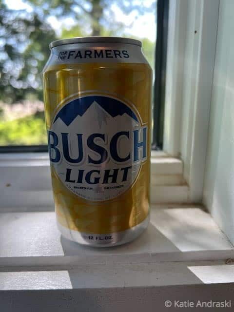 A can of Busch Light beer sitting on a windowsill with a blurred outdoor background.