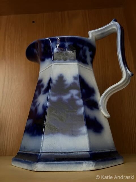 Blue and white ceramic pitcher with a unique handle design.