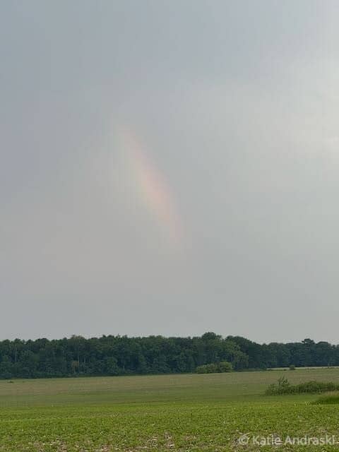 A faint rainbow appears in a cloudy sky.